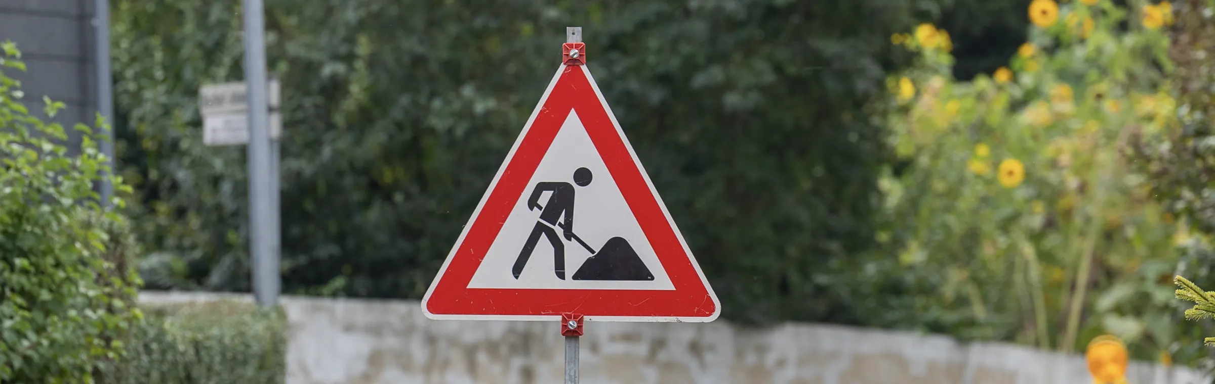 Auf dem Foto ist ein Straßenschild für Baustelle zu sehen, rot umrandetes Dreieck mit Bauarbeiter