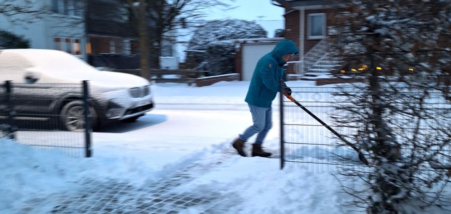 Das Foto zeigt einen Mann beim Schneeschieben