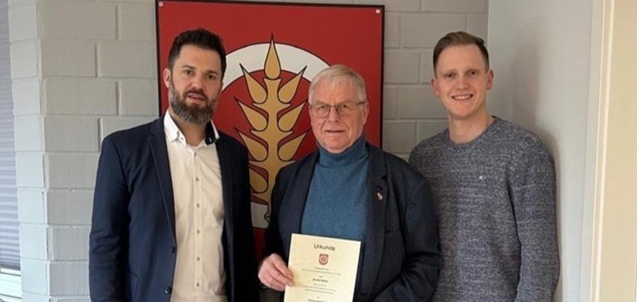 Auf dem Foto sind Marcel Litfin, Günter Weber und Maximilian Koch vor dem Wappen der Gemeinde Harsum zu sehen