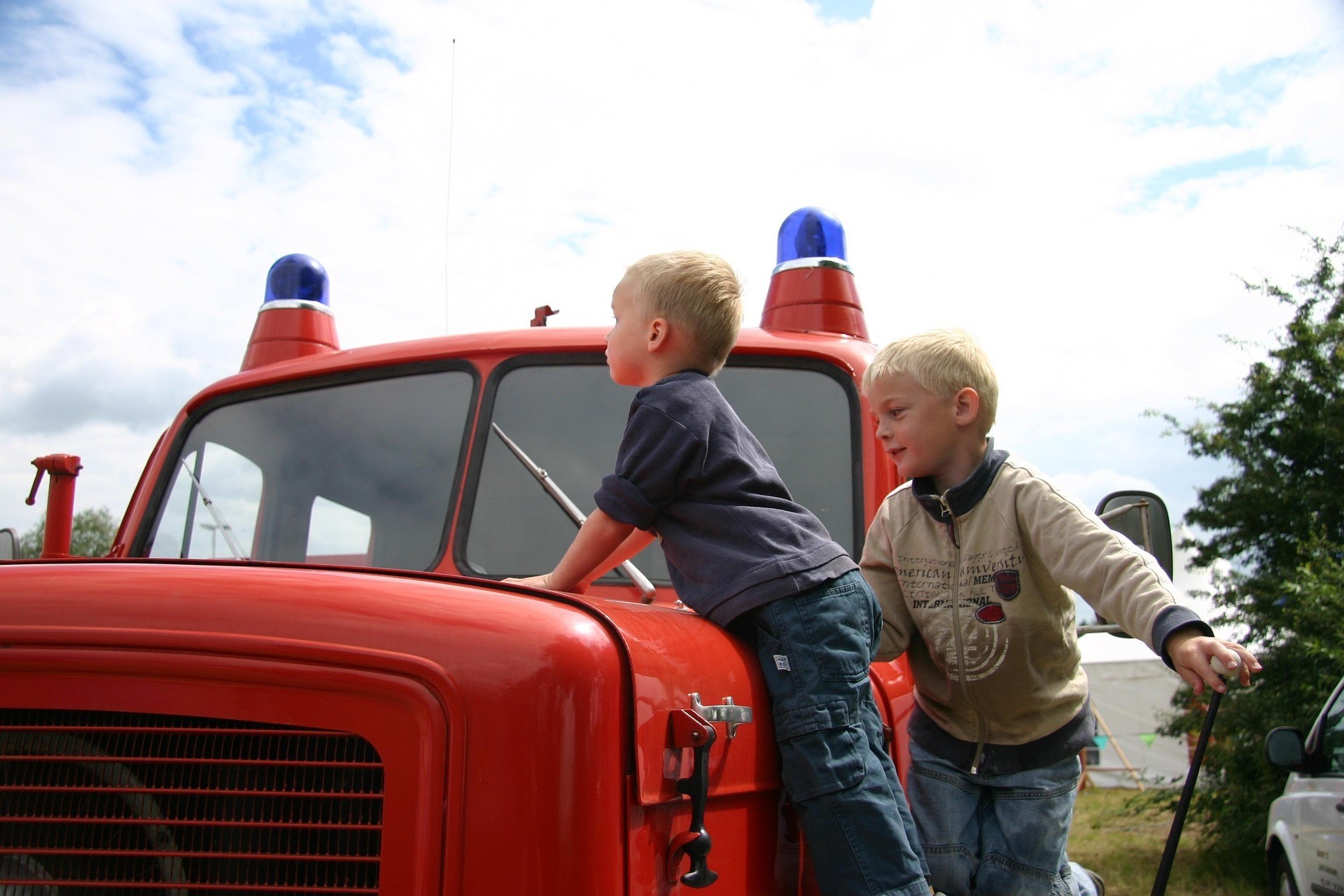 Auf dem Bild sind zwei Kinder auf einem Feuerwehrauto zu sehen