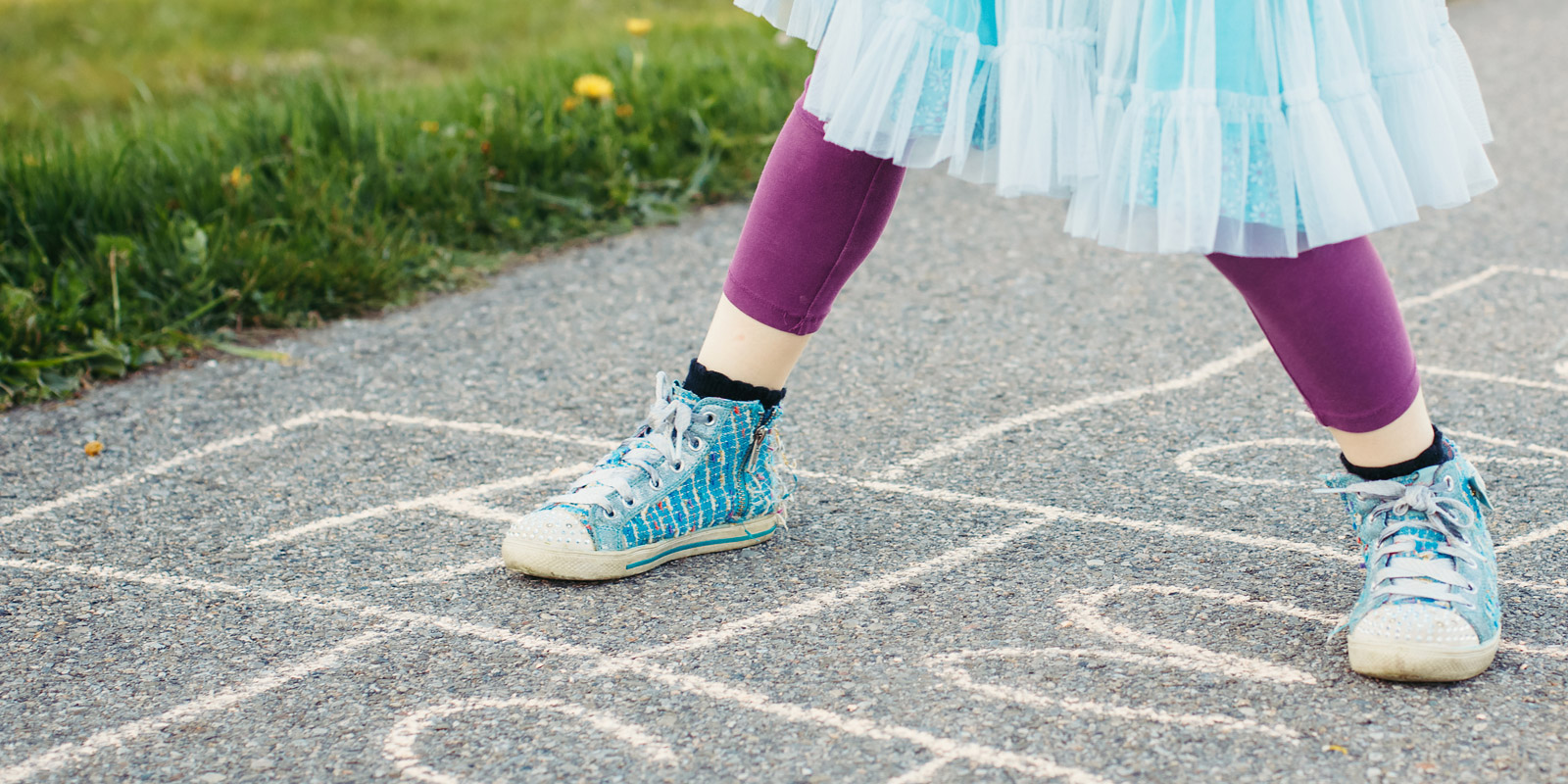 Auf dem Bild sind aufgemalte Hüpfekästchen zu sehen und Kinderschuhe