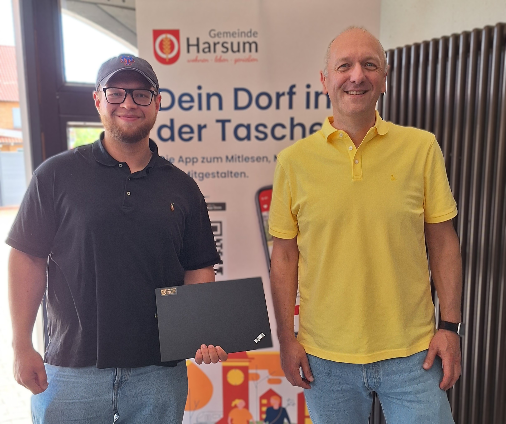 Auf dem Foto ist ein Mitarbeiter des Rathauses und ein Vertreter der Feuerwehr zu sehen, der einen Laptop in der Hand hält