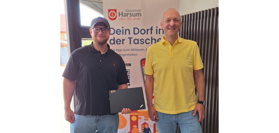 Auf dem Foto ist ein Mitarbeiter des Rathauses und ein Vertreter der Feuerwehr zu sehen, der einen Laptop in der Hand hält