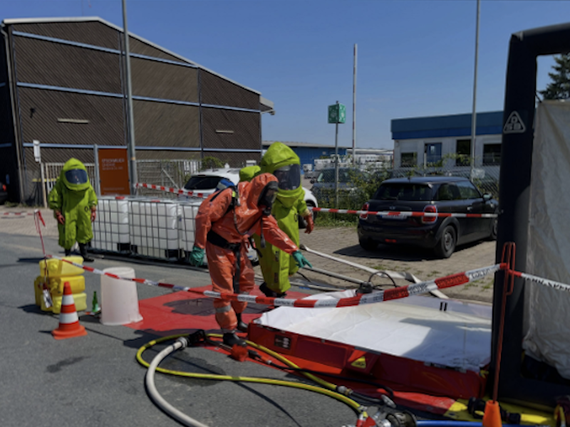 Auf dem Bild sind Feuerwehrleute mit Speialanzügen zu sehen die Abpumpen