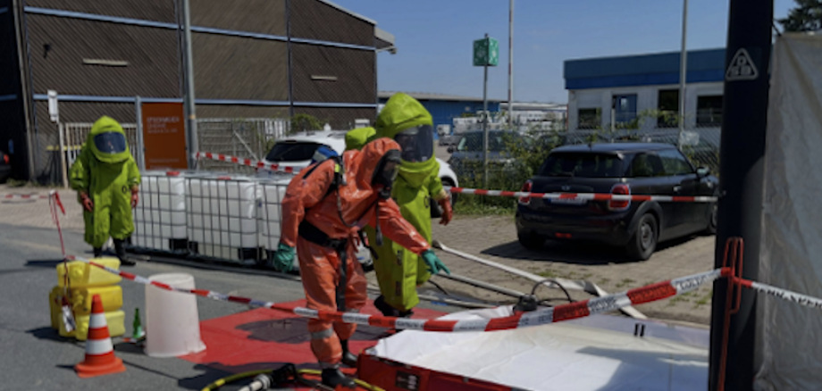 Auf dem Bild sind Feuerwehrleute mit Speialanzügen zu sehen die Abpumpen