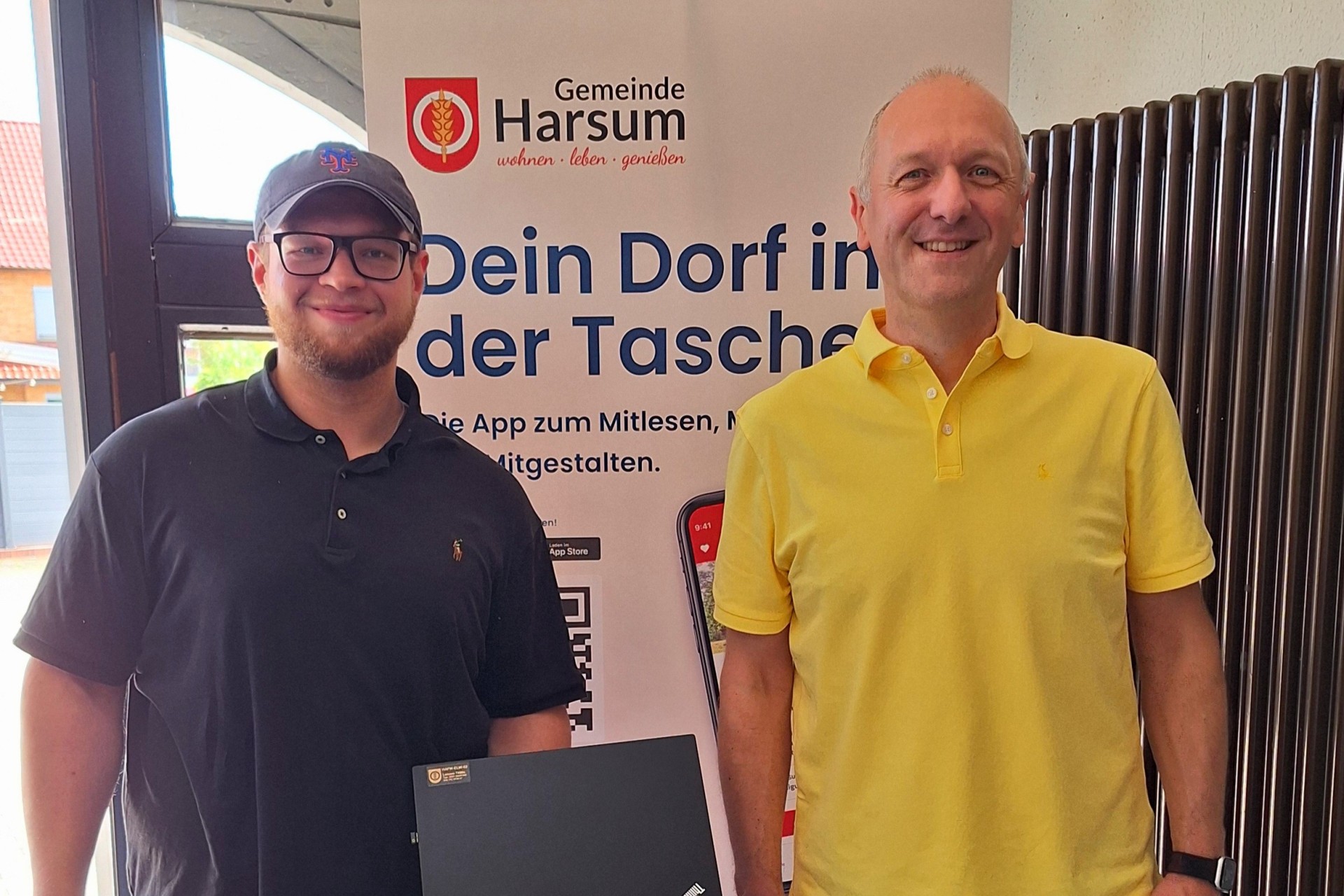 Auf dem Foto ist ein Mitarbeiter des Rathauses und ein Vertreter der Feuerwehr zu sehen, der einen Laptop in der Hand hält