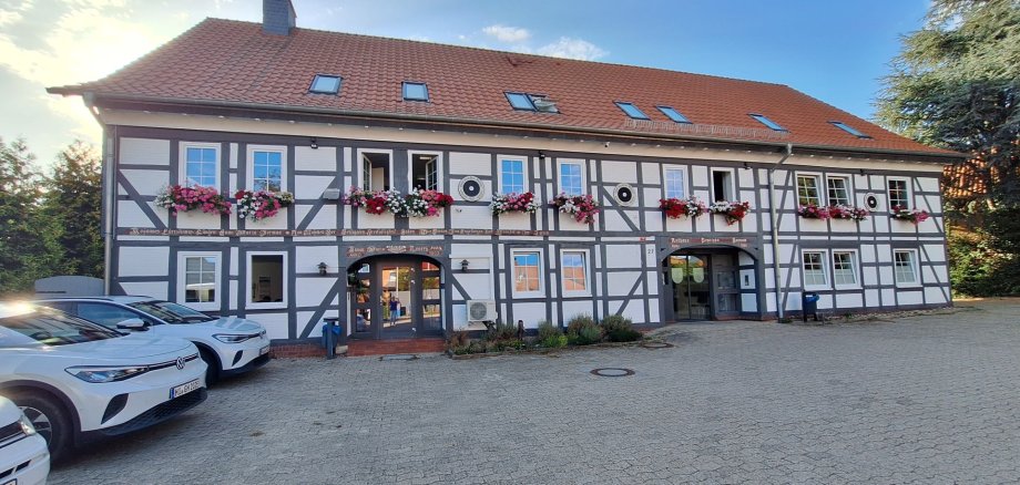 auf dem Foto ist das Harsumer Rathaus zu sehen. Die Geranien blühen in Blumenkästen an den Fenstern in der 1. Etage. Der Himmel ist blau