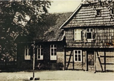 Das Bild zeigt eine alte Postkarte, die ehemalige Schule ist dort abgebildet