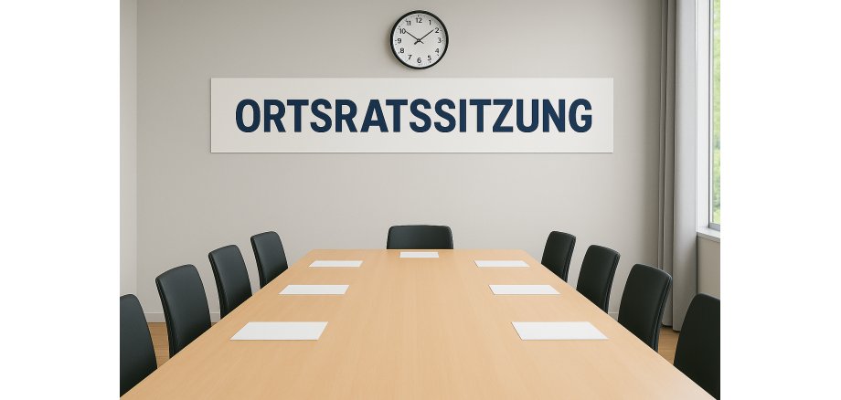 Auf dem Bild ist ein Raum mit einem großen Konferenztisch und Stühle zu sehen